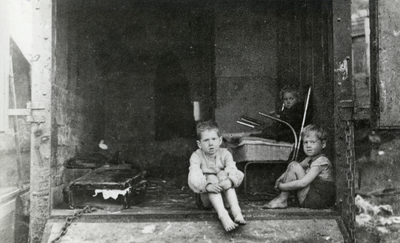 98423 Afbeelding van drie kinderen uit een gezin dat uit armoede onderdak heeft gevonden in een vrachtauto op het ...